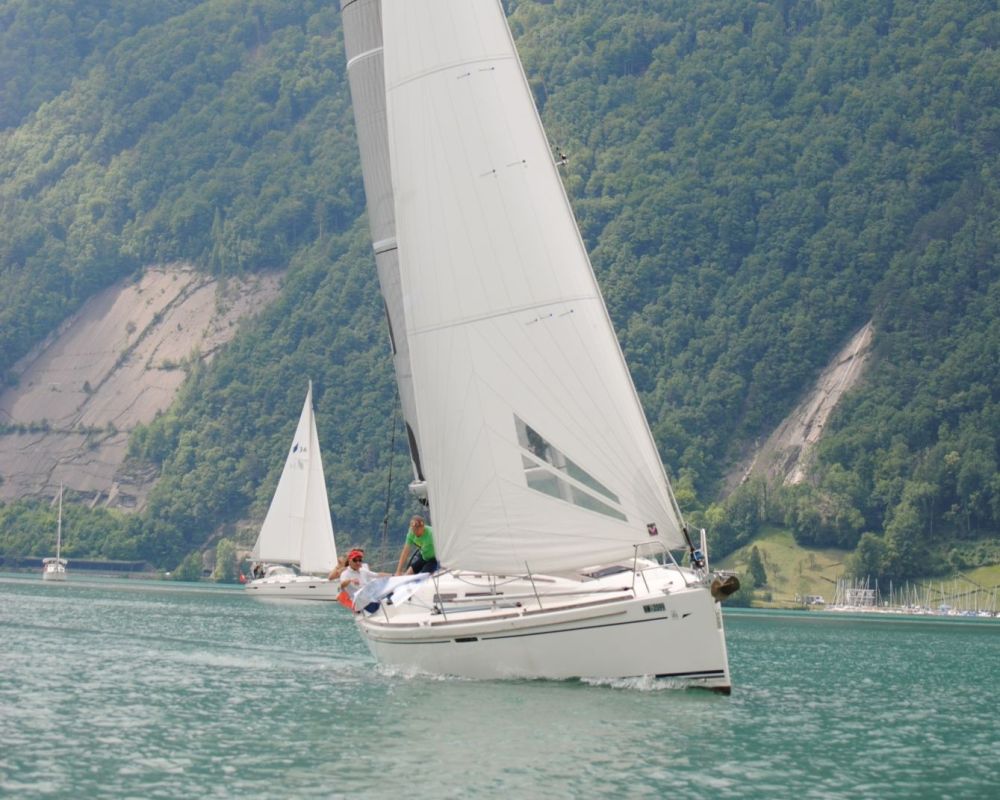 Yacht unter Segel vor bewaldeten Bergen