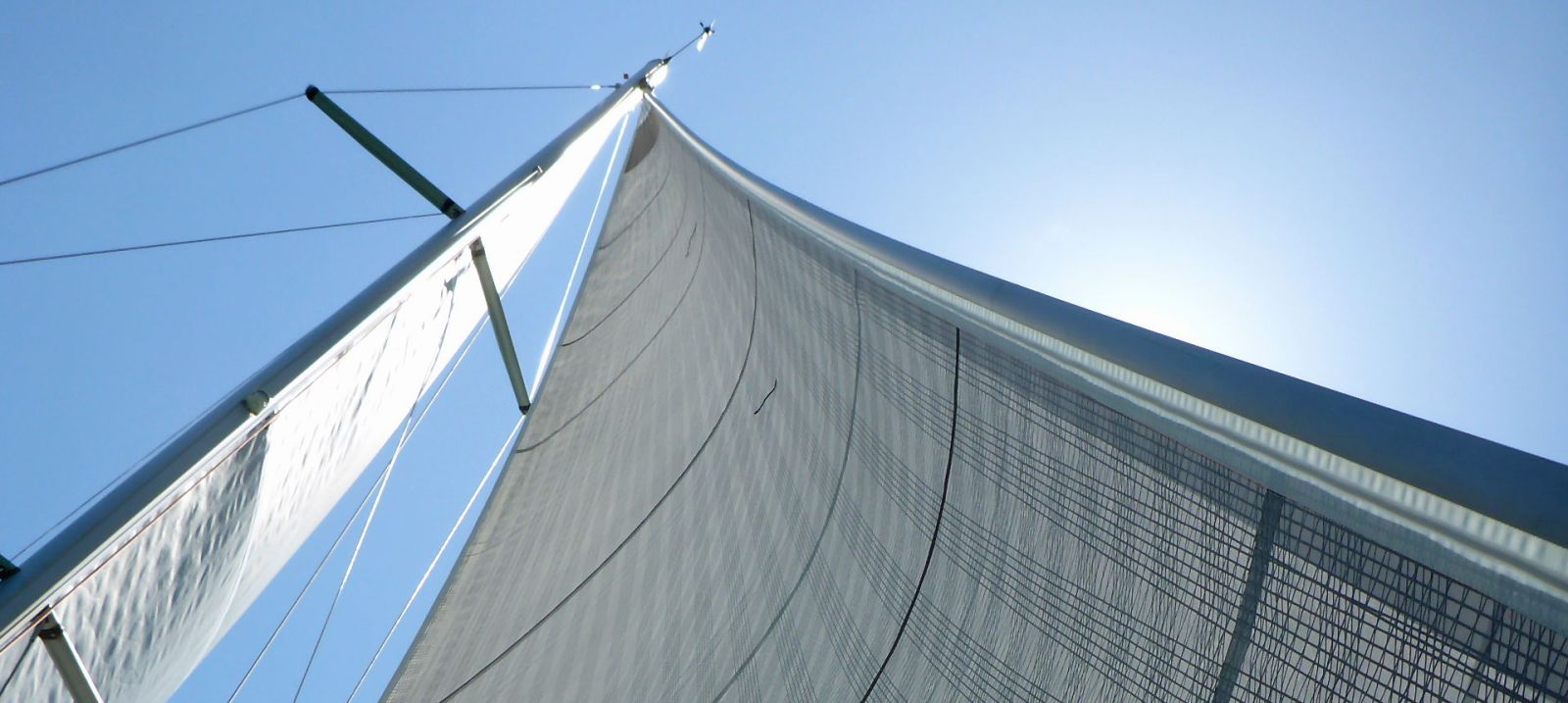 Blick an Mast und Segeln hinauf in den blauen Himmel