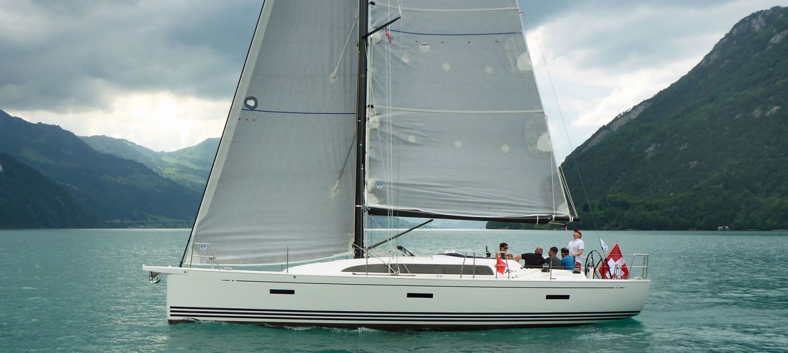 Yacht mit Crew unter Segel vor den Bergen am Urnersee